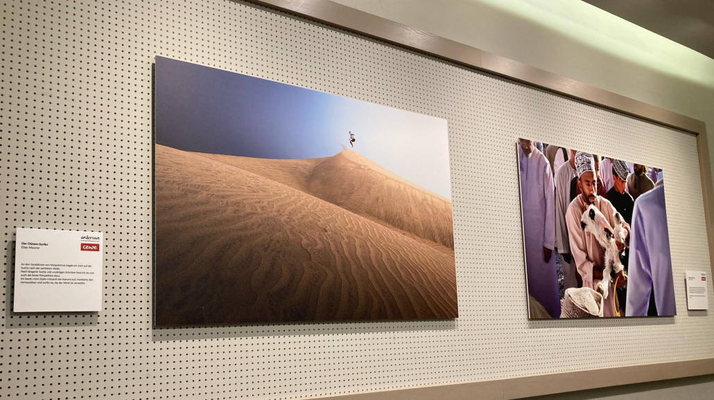 Ausstellungstitelbild der Reisefotoausstellung von Anderswo 2025. Zu sehen sind zwei Bilder an der Wand des Orpheum Graz