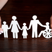 Bild von zwei Händen die Figuren aus Papier halten. Die Figuren stellen Kinder, eine Frau, einen Mann und eine Person im Rollstuhl da.