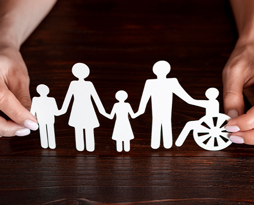 Bild von zwei Händen die Figuren aus Papier halten. Die Figuren stellen Kinder, eine Frau, einen Mann und eine Person im Rollstuhl da.
